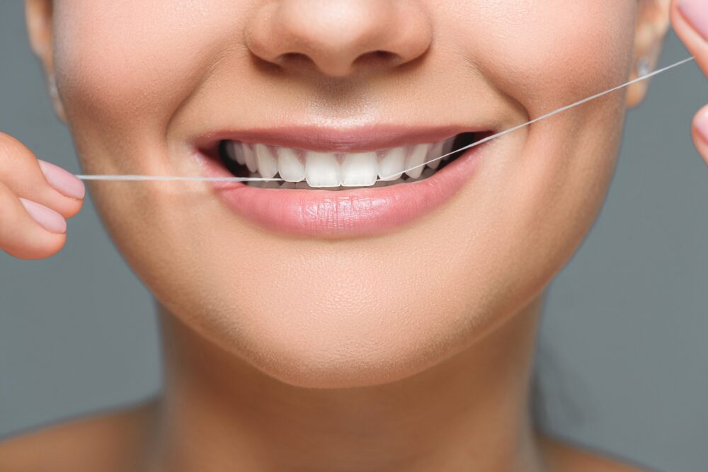 Dental floss cleaning between teeth to help prevent cavities in McKinney, TX